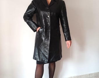 May include: A long black leather coat with a button closure and a belt. The coat has a collar and two pockets.