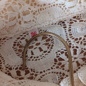 May include: Close-up of a white crocheted fabric with a size tag that says "36".