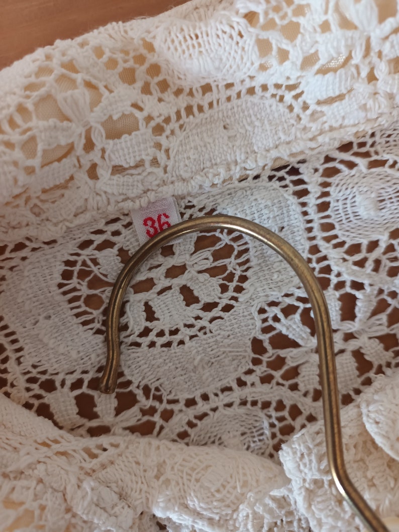 May include: Close-up of a white crocheted fabric with a size tag that says "36".