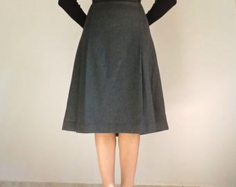 May include: A charcoal gray, knee-length skirt with a flared silhouette. The skirt is paired with a black long-sleeve top and black high-heeled shoes. The outfit is simple and elegant, suitable for various occasions.