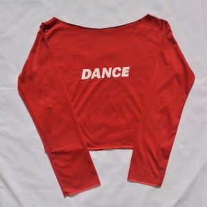 May include: A red long-sleeved shirt with a white "DANCE" graphic on the front.
