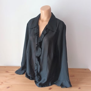 May include: A black sheer blouse with a ruffled collar and long sleeves.