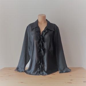 May include: A black long-sleeved blouse with a ruffled front and button closure.