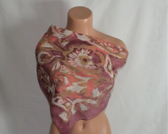 May include: A pink, orange, and white floral patterned silk scarf. The scarf is folded into a triangle shape and is draped over a mannequin's shoulders.