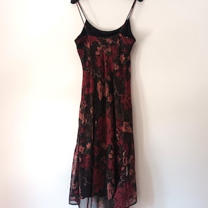 Peut inclure: Une robe maxi &agrave; fines bretelles &agrave; imprim&eacute; floral noir et rouge. La robe a un col haut et une jupe fluide.