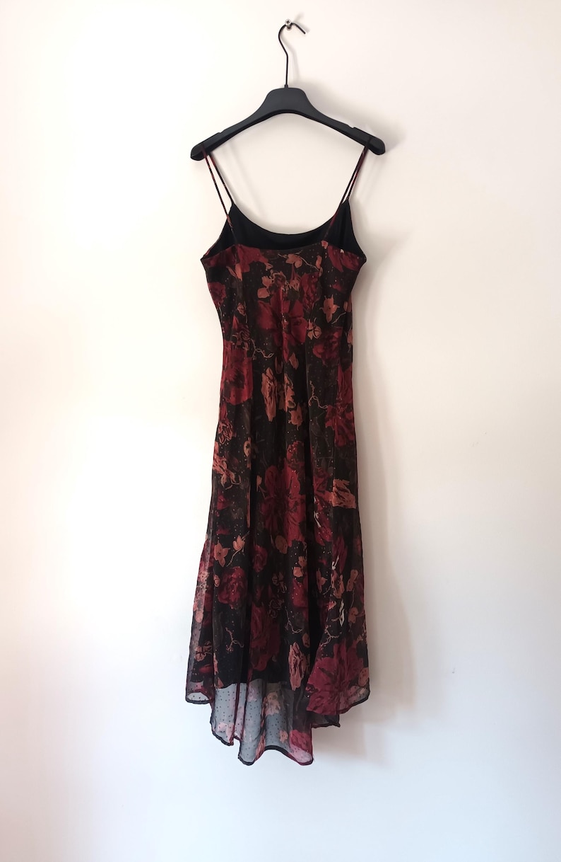 Peut inclure: Une robe maxi &agrave; fines bretelles &agrave; imprim&eacute; floral noir et rouge. La robe a un col haut et une jupe fluide.