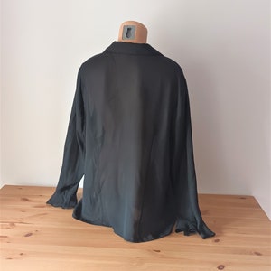 May include: A black long-sleeved shirt with a collared neckline. The shirt is made of a lightweight, sheer fabric.