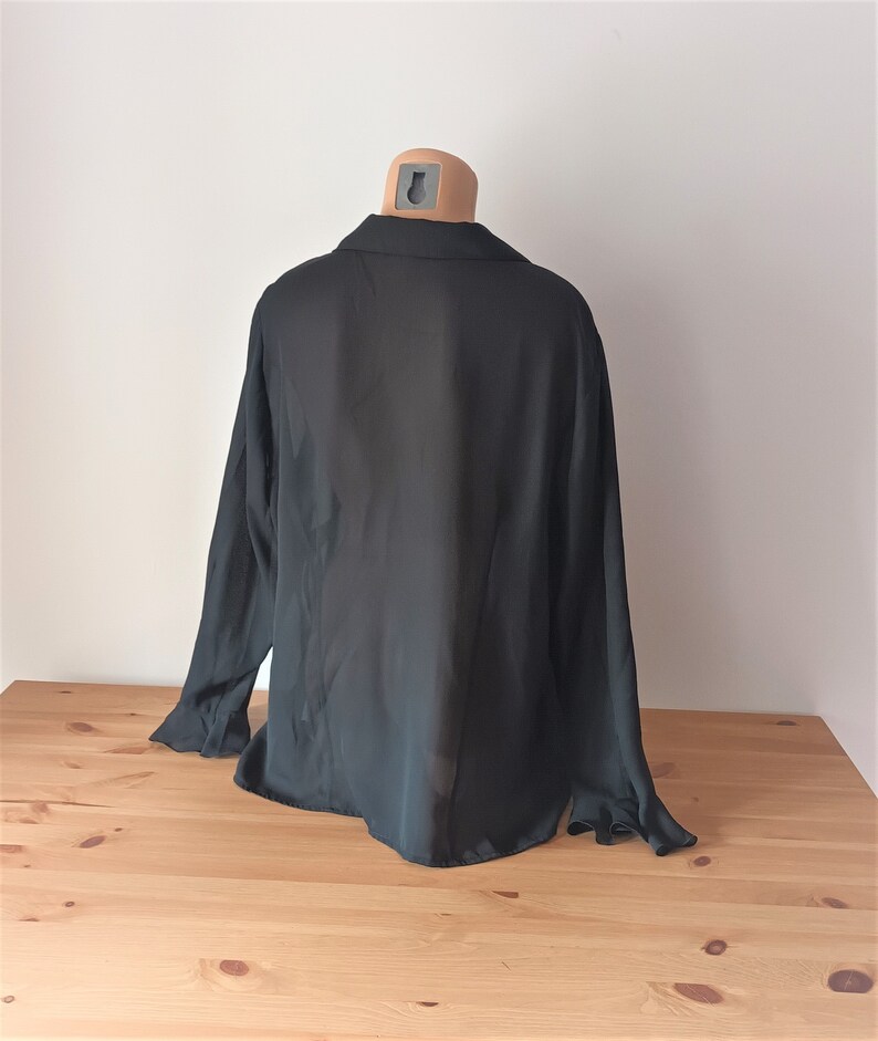May include: A black long-sleeved shirt with a collared neckline. The shirt is made of a lightweight, sheer fabric.