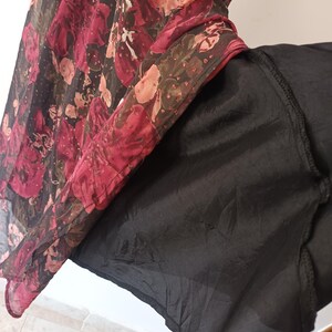 Peut inclure: Une jupe noire en tulle avec un imprim&eacute; floral superpos&eacute;. Le tissu superpos&eacute; est en tulle transparent avec un motif floral rouge, rose et vert.