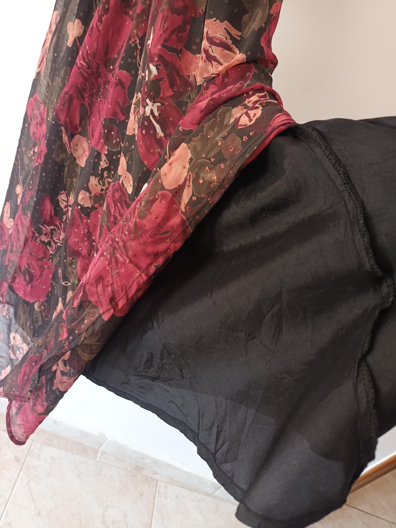 Peut inclure: Une jupe noire en tulle avec un imprim&eacute; floral superpos&eacute;. Le tissu superpos&eacute; est en tulle transparent avec un motif floral rouge, rose et vert.