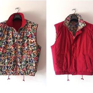 Puede incluir: Chaleco reversible con exterior rojo e interior estampado. El lado estampado presenta una mezcla de colores como azul, verde, rojo y marrón. El chaleco tiene cremallera, cuello alzado y cordón en la cintura.