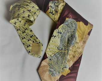 Può includere: Una cravatta di seta con un motivo paisley in tonalità di marrone, giallo e blu. La cravatta ha uno sfondo bordeaux con un motivo paisley giallo e blu.