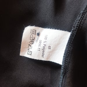 May include: White tag with black text that reads "100% Polyester 3856-111 48". The tag also has a black and white care label with symbols for washing, ironing, and drying.