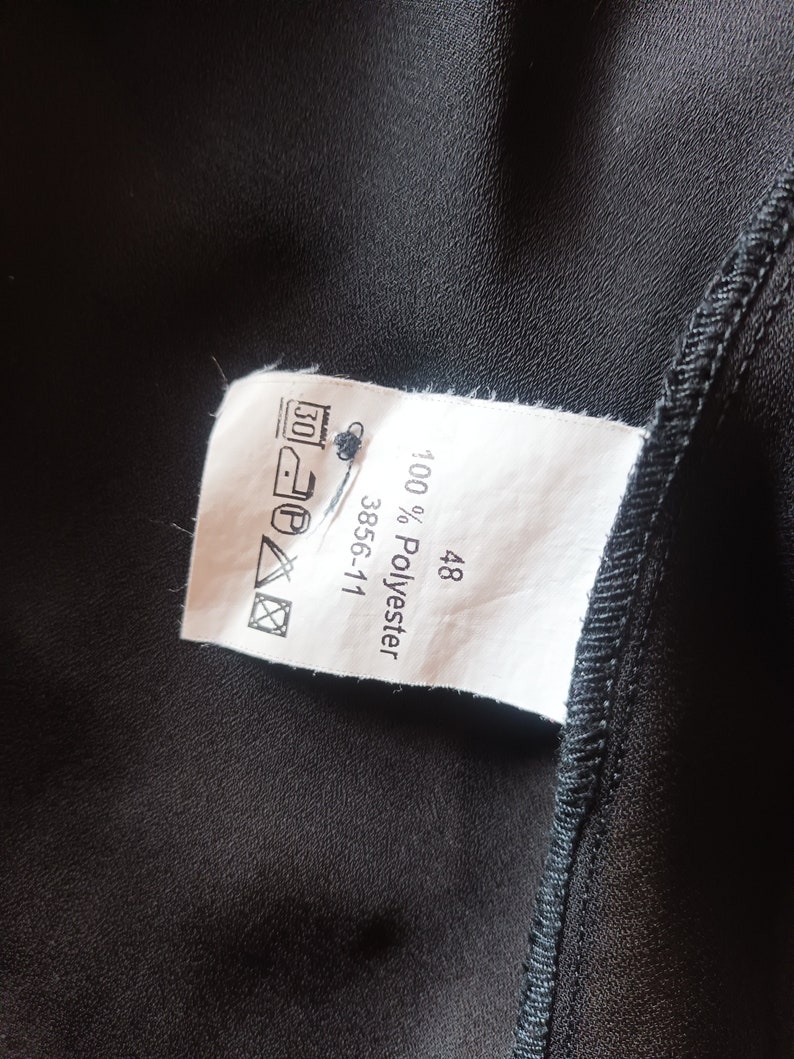 May include: White tag with black text that reads "100% Polyester 3856-111 48". The tag also has a black and white care label with symbols for washing, ironing, and drying.