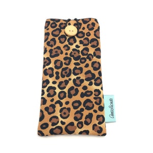 May include: A brown and black leopard print glasses case with a wooden button closure and a light blue label that says "Cami & Lucinda".