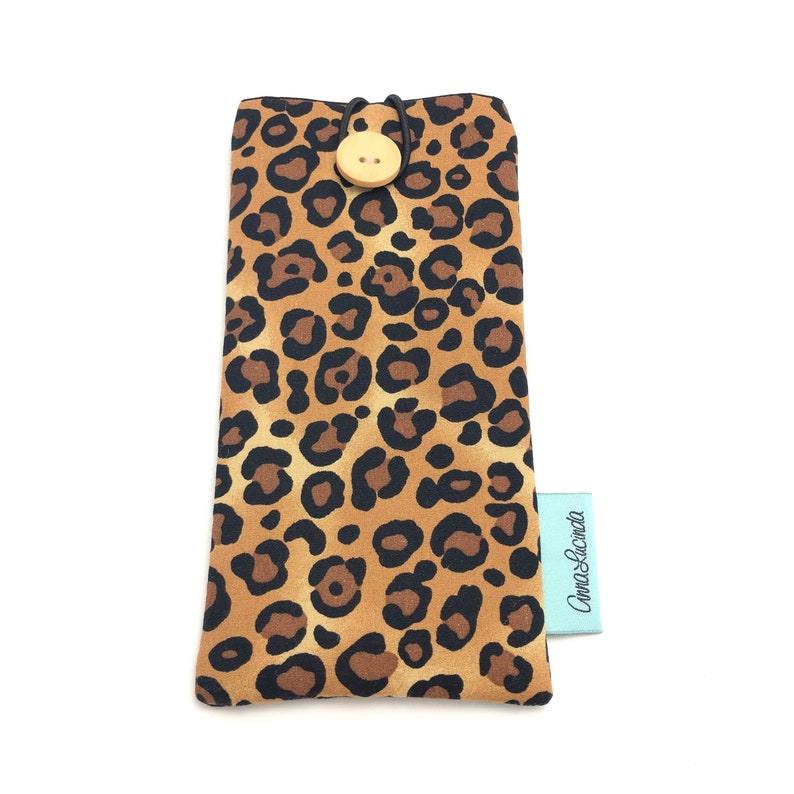 May include: A brown and black leopard print glasses case with a wooden button closure and a light blue label that says "Cami & Lucinda".