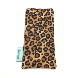 May include: A brown and black leopard print eyeglass case with the text "Anna & Lucinda" on a white tag.