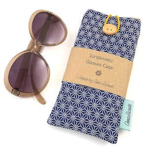 May include: A blue and white patterned fabric sunglasses case with a brown label that reads "Sunglasses/Glasses Case Made by Anna Lucinda".