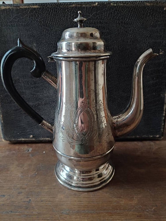 Large silver metal jug decorated with virgin and plant medallions, tea coffee