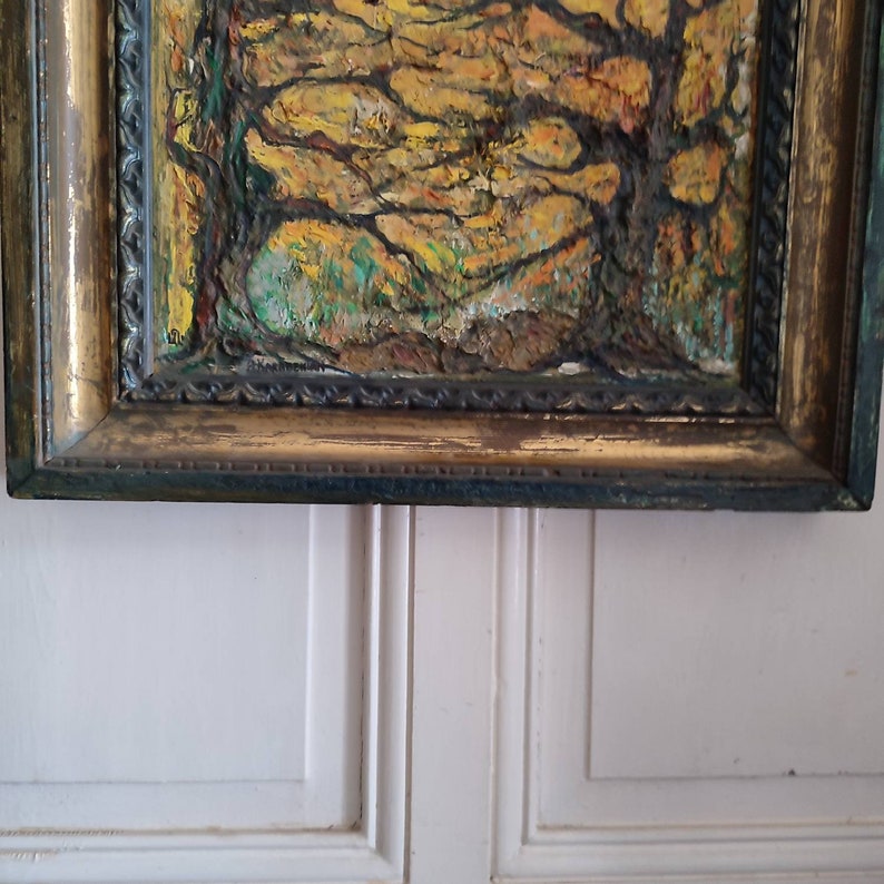 May include: A framed oil painting depicting a forest scene with trees in shades of yellow, green, and brown. The frame is gold with a dark brown inner edge.
