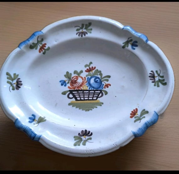 Small antique earthenware dish with painted decoration of a flower basket, signed R