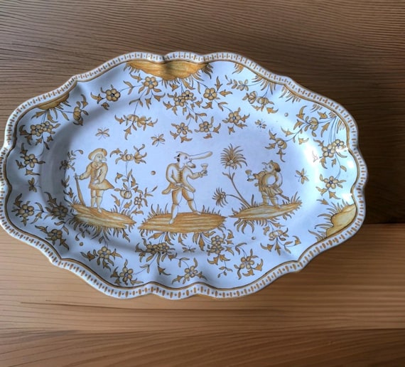 Moustiers? Large earthenware dish decorated with grotesque figures, butterflies and flowers. French earthenware.