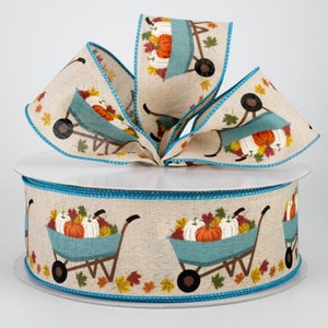May include: A roll of beige burlap ribbon with a turquoise trim. The ribbon features a repeating pattern of a blue wheelbarrow filled with pumpkins and fall leaves.
