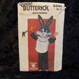 May include: A vintage sewing pattern for a Bugs Bunny costume. The pattern is from Quick-Butterick and is number 6348. The pattern is for a one-size costume and includes a cartoon image of Bugs Bunny holding a carrot.
