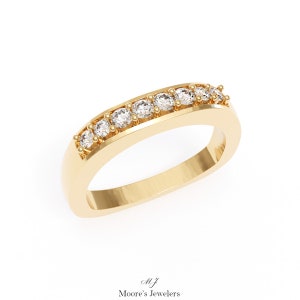 May include: A gold band ring with a row of small, clear diamonds set in a curved, slightly raised channel.