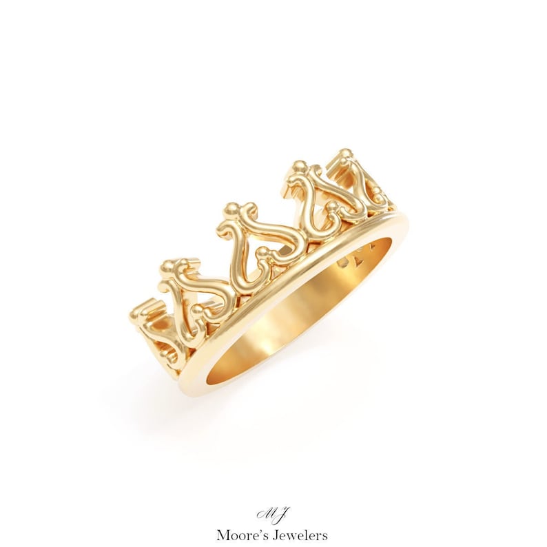 May include: A gold crown ring with a delicate, intricate design. The ring is made of solid gold and features a detailed crown motif.