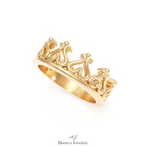 May include: A gold crown ring with a delicate, intricate design. The ring is made of polished gold and features a series of connected, curved shapes that resemble a crown.