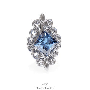 May include: A silver ring featuring a blue square-shaped gemstone set within a decorative filigree design.