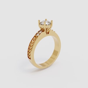 Könnte beinhalten: Ein goldener Ring mit einem einzelnen Diamanten in der Mitte und einem dekorativen Band aus kleinen Diamanten und blattartigen Designs.