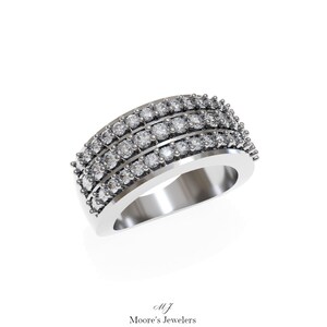 May include: A silver band ring with three rows of small, round, clear stones.
