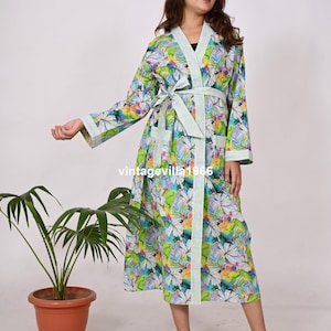 May include: A long, white robe with a green, blue and pink floral print. The robe has a tie belt and long sleeves. The robe is made of cotton and is lightweight and comfortable.