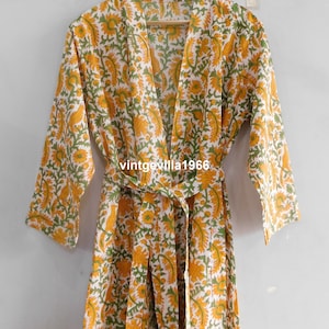 May include: A white cotton robe with a yellow and green floral print. The robe has a tie belt and long sleeves.