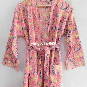 May include: A pink cotton robe with a floral print and a tie belt. The robe has long sleeves and a  deep V-neck.