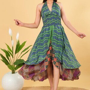 May include: A colourful halter-neck dress with a layered design. The dress has a green and blue patterned top, a patterned skirt with a high-low hemline, and an orange and purple underlayer. The dress is suitable for a variety of occasions.