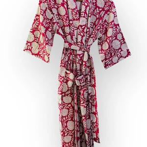 May include: A burgundy floral print robe with a matching belt, hanging on a wooden hanger. The robe features a white floral pattern and white trim along the edges. The robe is made of a soft, lightweight fabric.