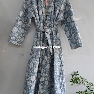 May include: A long, quilted robe in a blue and white floral pattern. The robe has long sleeves, a tie belt, and a pink floral lining. The text "vintagevilla1966" is visible on the robe.