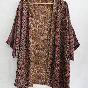 May include: A patterned kimono-style jacket with a brown paisley center panel and dark blue side panels. The side panels feature a floral and geometric design in red and yellow. The sleeves are a burgundy diamond pattern.