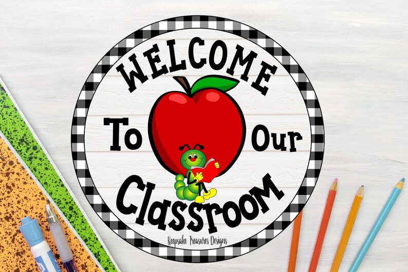 May include: A round classroom sign with a black and white checkered border. The sign features the words "WELCOME To Our Classroom" in black text. A red apple with a green leaf and a cartoon caterpillar reading a book are in the center.