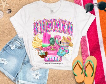 May include: White t-shirt featuring a colourful graphic design that reads "Summer Vibes". The design includes a pink flamingo, a watermelon, a pineapple, and a popsicle.