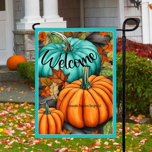 May include: A teal and orange welcome garden flag with a teal pumpkin, two orange pumpkins, and fall leaves. The text "Welcome" is written in black cursive on the flag.
