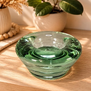 Peut inclure: Un bol en verre circulaire et épais avec une teinte vert émeraude translucide. Le bol présente un bord large et arrondi ainsi qu'un bassin profond et lisse, mettant en valeur une construction solide avec des anneaux concentriques subtils.