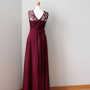 May include: A burgundy maxi dress with a lace bodice and a sash tie at the waist.