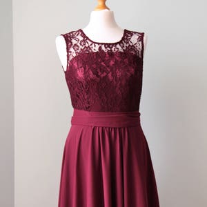 May include: A burgundy sleeveless dress with a lace bodice and a full skirt. The dress has a simple, elegant design.