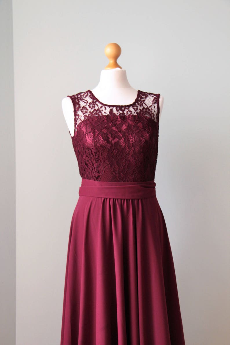 May include: A burgundy sleeveless dress with a lace bodice and a full skirt. The dress has a simple, elegant design.