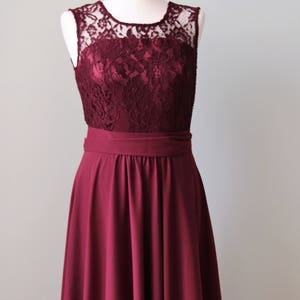 May include: A burgundy sleeveless dress with a lace bodice and a full skirt. The dress has a satin-like finish and a simple, elegant design.