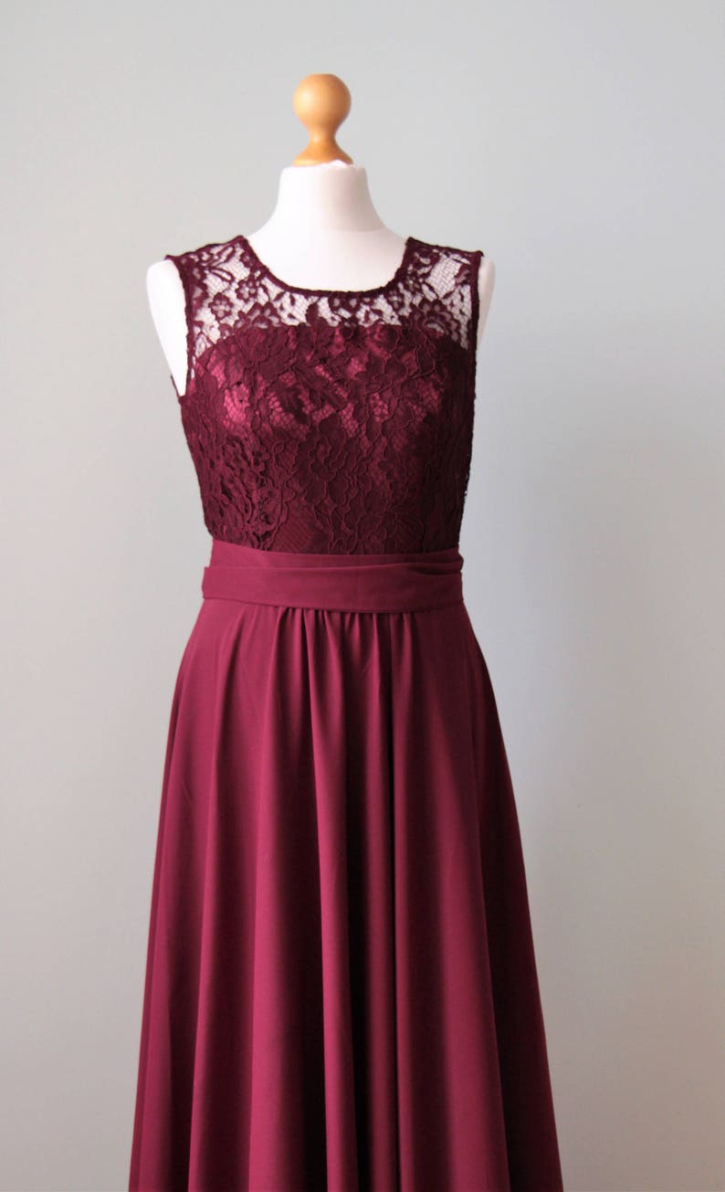 May include: A burgundy sleeveless dress with a lace bodice and a full skirt. The dress has a satin-like finish and a simple, elegant design.